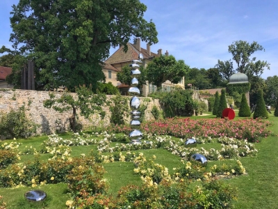 La sculpture de Pol Quadens entourée de roses en fleurs.
