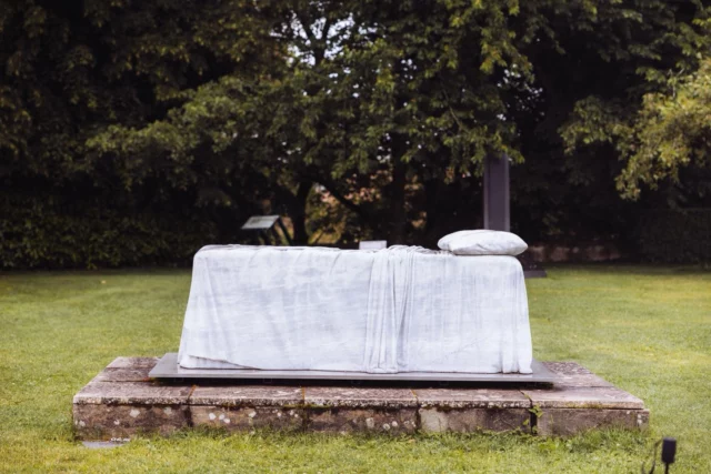 🛏️ “The Bed” – Dorothy Cross au Château de Vullierens 🛏️

Au cœur des somptueux jardins du Château de Vullierens, la sculpture The Bed de l’artiste irlandaise Dorothy Cross fascine par sa force poétique et sa matérialité brute. Sculptée dans le marbre, cette œuvre évoque un lit abandonné, à la fois lieu de repos, de rêve et de souvenir.

Immobile et silencieux, le lit semble surgir de la terre comme une trace d’humanité figée dans la pierre. Le contraste entre la douceur du thème et la froideur du marbre crée une tension puissante : le lit devient un monument à l’absence, à la mémoire, à l’intime.

🌿 Intégrée au parcours d’art contemporain du domaine, The Bed dialogue avec la nature environnante, les iris en fleurs et la majesté des Alpes en arrière-plan. Une œuvre à la fois discrète et bouleversante.

📍 À découvrir lors de votre visite aux Jardins du Château de Vullierens, où art et paysage se rencontrent en parfaite harmonie. Photo @stacey_camera 

#DorothyCross #TheBed #chateaudevullierens  #SculptureContemporaine #Marbre #ArtEtNature #Exposition2025 #JardinInspiré #ArtIrlandais  #SculptureArt #sculpture_art
